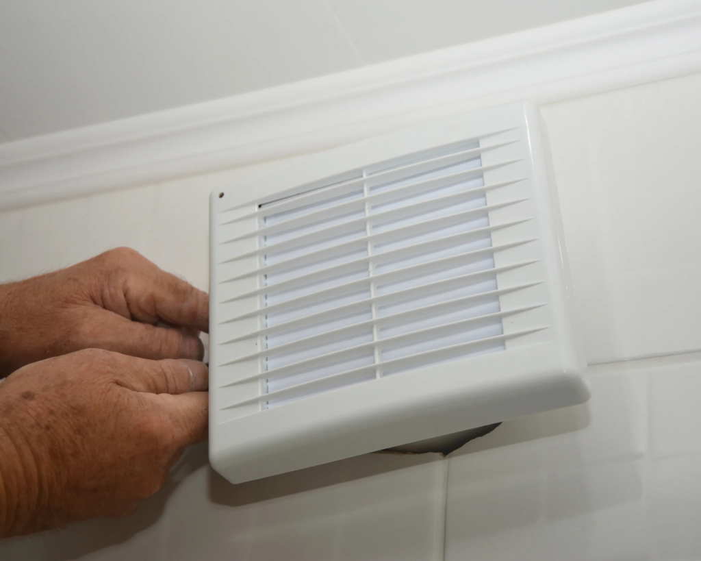 Electrician installing a bathroom exhaust ventilation fan.