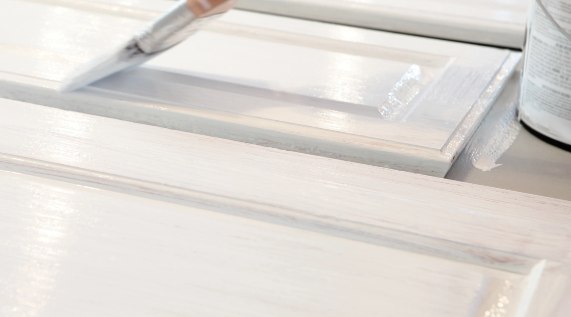 Painter refinishing and repainting kitchen cabinet doors