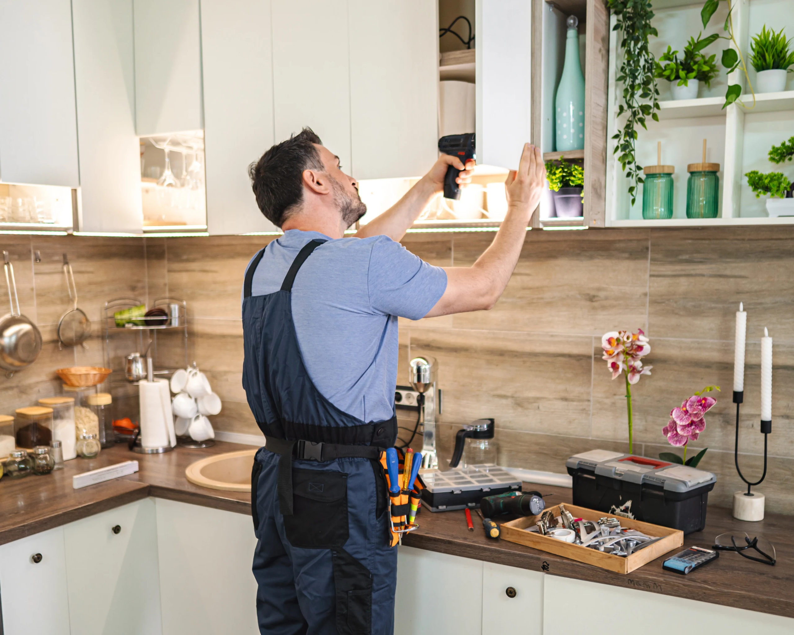 Technician fixing cabinet hinges and upgrading drawer hardware
