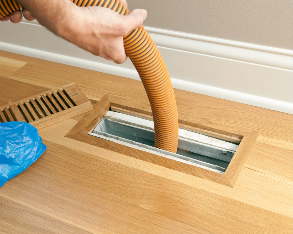 HVAC technician cleaning air ducts using professional vacuum equipment.