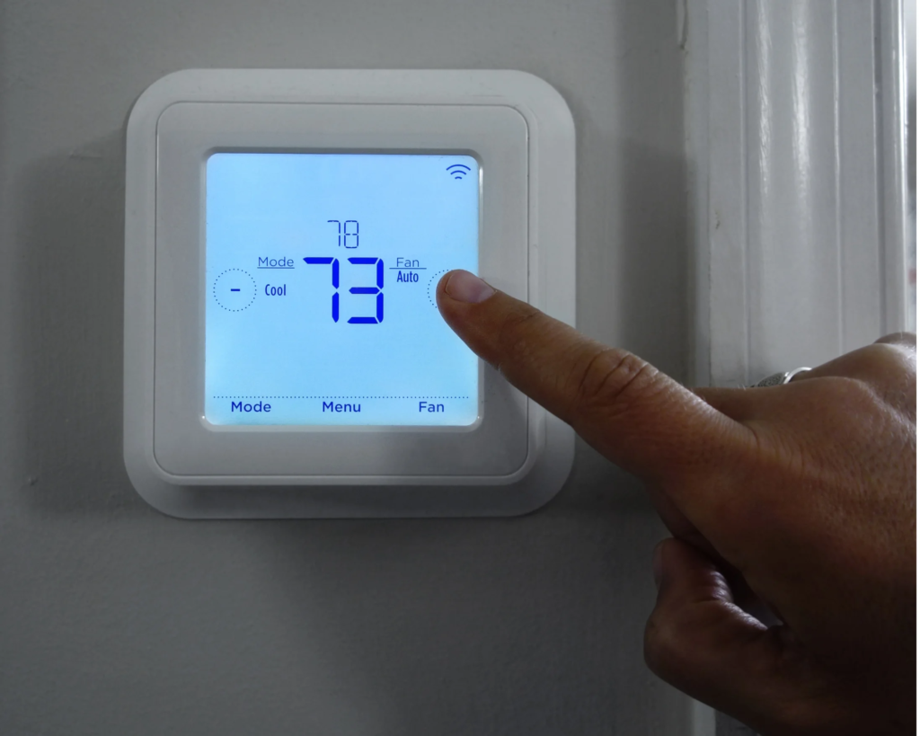 Technician installing a Nest smart thermostat on a home wall.