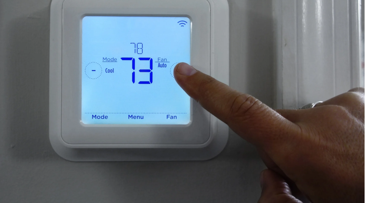 Technician installing a Nest smart thermostat on a home wall.